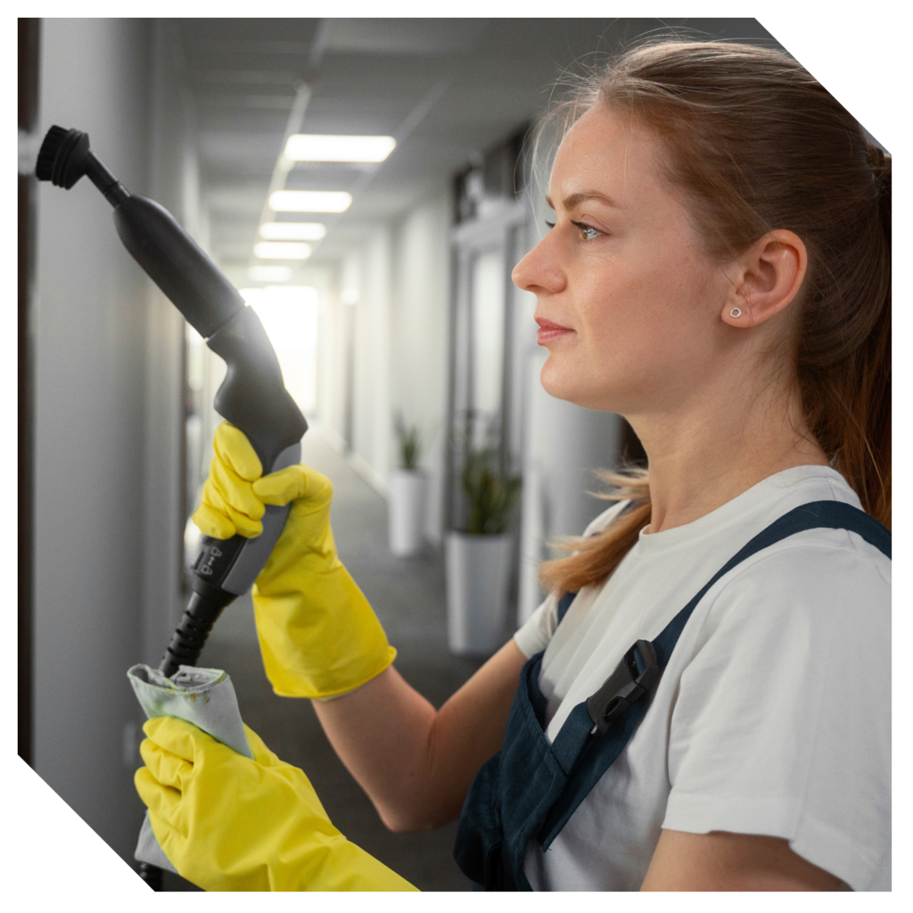 A woman wearing yellow gloves uses a cleaning tool in a hallway, expertly performing window cleaning to keep the interior sparkling.