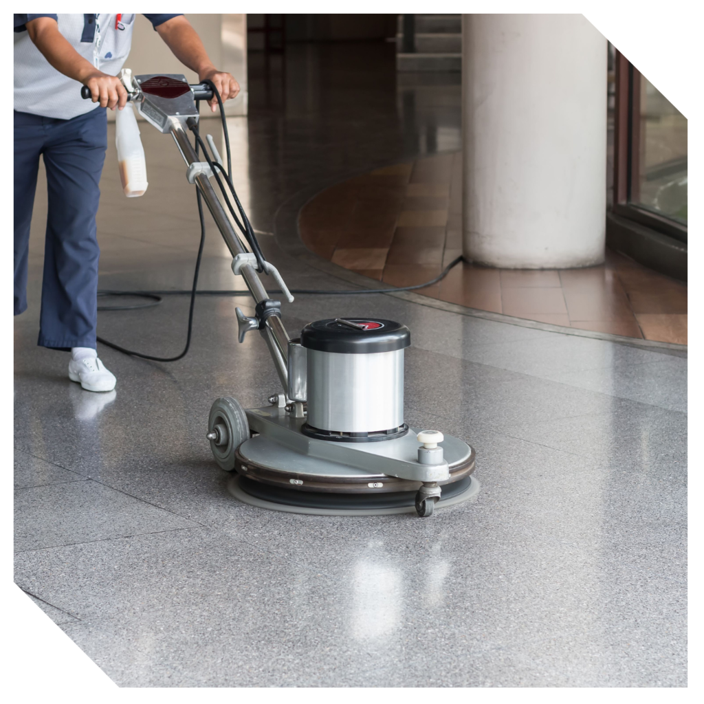 A person operates a floor polishing machine on a shiny, tiled surface inside a building, expertly engaged in marble polishing to enhance the floor's elegance.